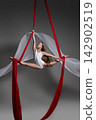 Teen girl performing split on red aerial silks 142902519