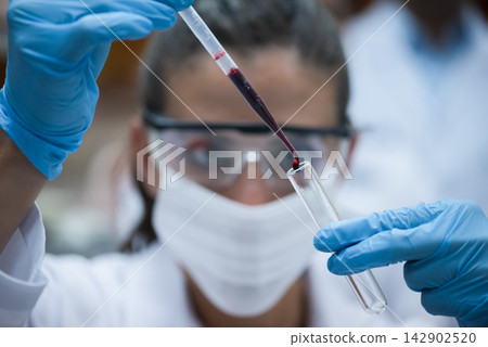 Young medical technician performing blood test in laboratory with protective gloves and mask Young medical technician performing blood test in laboratory with protective gloves and mask 142902520
