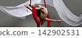 Teen aerialist reaching from wrapped red silks 142902531