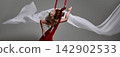 Young gymnast curving around red aerial silks 142902533