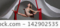 Young aerialist holding wide split on red silks 142902535