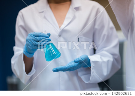 Middle Eastern doctors and medical technician handling blue liquid in blood testing laboratory Middle Eastern doctors and medical technician handling blue liquid in blood testing laboratory 142902651