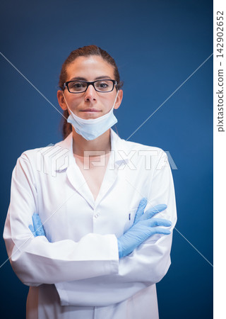 Young female doctor and lab technician wearing mask and gloves in a clinical blood testing laboratory Young female doctor and lab technician wearing mask and gloves in a clinical blood testing laboratory 142902652