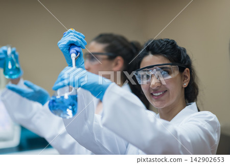 Middle Eastern women doctors and lab technicians smiling while performing blood testing with pipette in clinical laboratory Middle Eastern women doctors and lab technicians smiling while performing blood testing with pipette in clinical laboratory 142902653