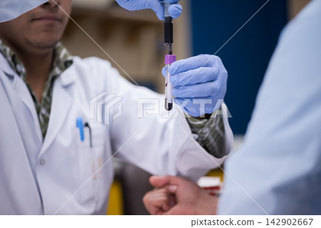 Young doctors and medical technician performing a blood test in a clinical laboratory with gloves Young doctors and medical technician performing a blood test in a clinical laboratory with gloves 142902667