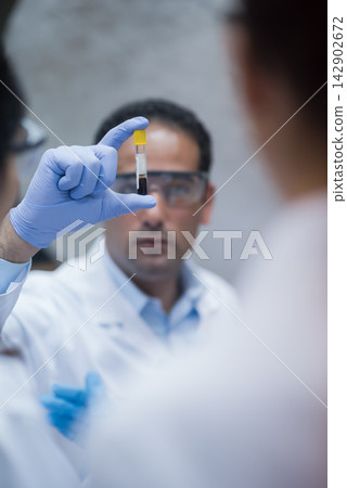 Middle Eastern doctor examining a blood sample in a clinical lab with technician during testing and diagnostics Middle Eastern doctor examining a blood sample in a clinical lab with technician during testing and diagnostics 142902672