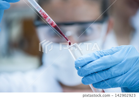 Middle Eastern medical technician performing blood test in laboratory while young doctor observes closely Middle Eastern medical technician performing blood test in laboratory while young doctor observes closely 142902923