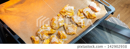 Hands hold a baking tray with deep-fried chicken nuggets covered in flour. The scene is set in a home kitchen with light colors and a casual atmosphere, banner Hands hold a baking tray with deep-fried chicken nuggets covered in flour. The scene is set in a home kitchen with light colors and a casual atmosphere, banner 142902938