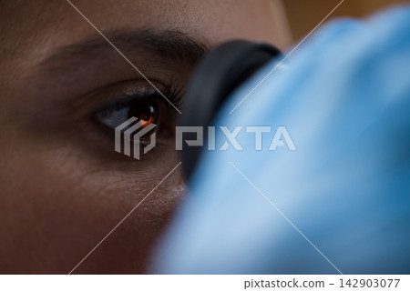 Young doctor examining blood sample through microscope eyepiece in medical testing laboratory 142903077