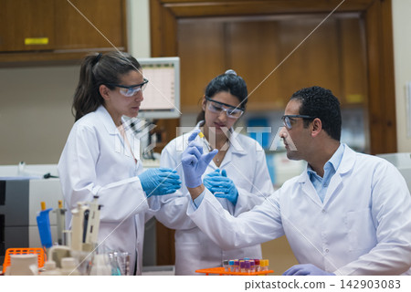 Young medical team of lab technicians and doctors examining blood sample in clinical laboratory Young medical team of lab technicians and doctors examining blood sample in clinical laboratory 142903083