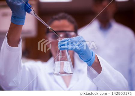 Young doctors and medical technician working with pipette and flask in clinical laboratory testing Young doctors and medical technician working with pipette and flask in clinical laboratory testing 142903175