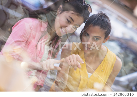 Couple shopping for a wedding ring with friends pointing at a jewelry display Couple shopping for a wedding ring with friends pointing at a jewelry display 142903310