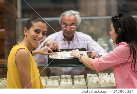 Middle Eastern couple shopping for a wedding ring with friends and family at a jewelry store Middle Eastern couple shopping for a wedding ring with friends and family at a jewelry store 142903324