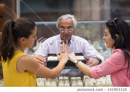 Middle Eastern couple choosing a wedding ring with friends and family at a jewelry store Middle Eastern couple choosing a wedding ring with friends and family at a jewelry store 142903326