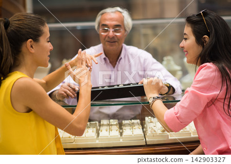 Middle Eastern couple shopping for a wedding ring with friends and family at a jewelry store Middle Eastern couple shopping for a wedding ring with friends and family at a jewelry store 142903327