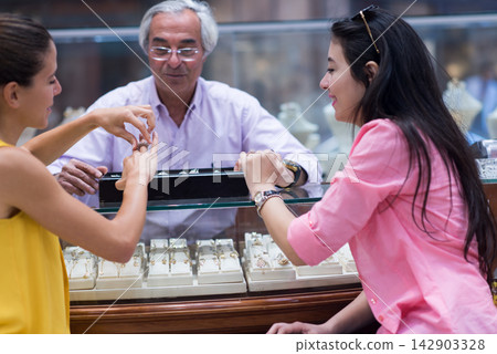Middle Eastern couple shopping for a wedding ring with friends and family at a jewelry store Middle Eastern couple shopping for a wedding ring with friends and family at a jewelry store 142903328