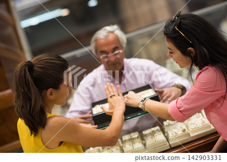 Middle Eastern couple shopping for wedding rings with friends and family at a jewelry store Middle Eastern couple shopping for wedding rings with friends and family at a jewelry store 142903331