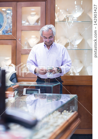 Middle Eastern couple buying wedding ring in a jewelry store with family and friends present Middle Eastern couple buying wedding ring in a jewelry store with family and friends present 142903427