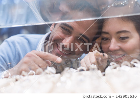 Couple buying wedding rings with friends and family while smiling and choosing a ring at a jewelry store 142903630