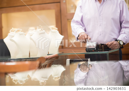 Middle Eastern couple shopping for a wedding ring with family and friends at a jewelry store Middle Eastern couple shopping for a wedding ring with family and friends at a jewelry store 142903631
