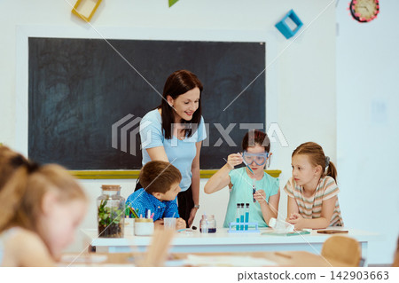 Teacher guiding elementary students during a hands-on science experiment in a bright classroom Teacher guiding elementary students during a hands-on science experiment in a bright classroom 142903663