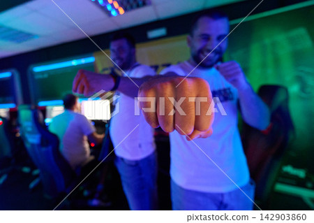 Two Friends Gamers Fist Bump In Neon Esports Gaming Room Celebrating Victory And Team Spirit Two Friends Gamers Fist Bump In Neon Esports Gaming Room Celebrating Victory And Team Spirit 142903860