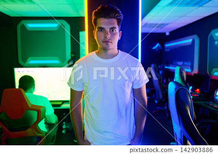 Young Gamer Standing in Neon Esports Arena With Computers and Gaming Chairs Young Gamer Standing in Neon Esports Arena With Computers and Gaming Chairs 142903886