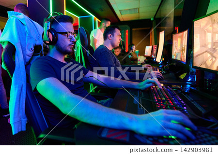 Team of Focused Gamers Playing Competitive Video Games in Neon-Lit Esports Gaming Arena Team of Focused Gamers Playing Competitive Video Games in Neon-Lit Esports Gaming Arena 142903981