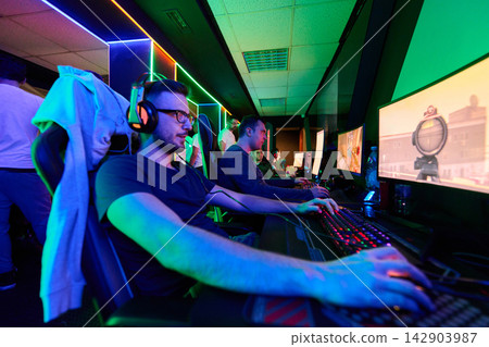 Team of Gamers Competing in a Neon LAN Gaming Room With Headsets and RGB Keyboards Team of Gamers Competing in a Neon LAN Gaming Room With Headsets and RGB Keyboards 142903987