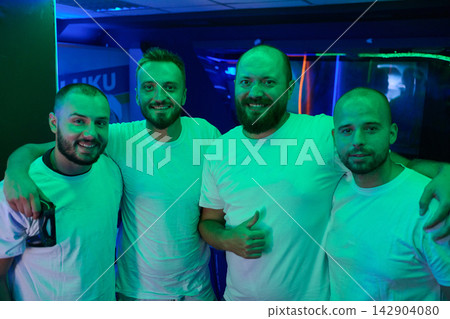 Four Friends Smiling Together at Neon-Lit Nightclub Party Showing Camaraderie and Fun 142904080