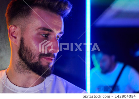 Bearded Man Portrait in Neon Light at Nightclub With Moody Blue and Purple Lighting Bearded Man Portrait in Neon Light at Nightclub With Moody Blue and Purple Lighting 142904084