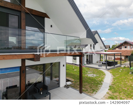 Modern family home with glass balcony and spacious patio in a suburban neighborhood Modern family home with glass balcony and spacious patio in a suburban neighborhood 142904097