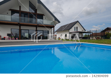 Modern family house with blue outdoor swimming pool and spacious backyard patio area Modern family house with blue outdoor swimming pool and spacious backyard patio area 142904099