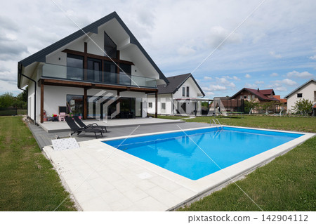 Modern family home with outdoor swimming pool and spacious backyard patio in suburban neighborhood Modern family home with outdoor swimming pool and spacious backyard patio in suburban neighborhood 142904112