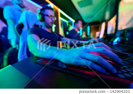 Competitive PC Gaming Team Playing in Neon Esports Arena With Headsets and RGB Lighting Competitive PC Gaming Team Playing in Neon Esports Arena With Headsets and RGB Lighting 142904203