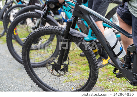 Group of mountain bikes lined up with riders ready for off-road cycling on a gravel trail 142904830