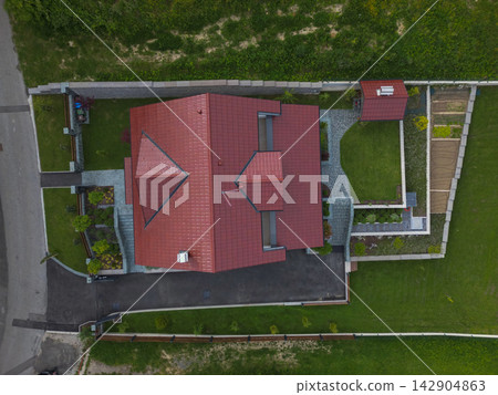 Aerial drone view of a suburban house with red roof, landscaped yard and driveway Aerial drone view of a suburban house with red roof, landscaped yard and driveway 142904863