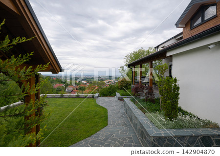 Modern suburban house with stone patio, garden and panoramic view over town and countryside Modern suburban house with stone patio, garden and panoramic view over town and countryside 142904870