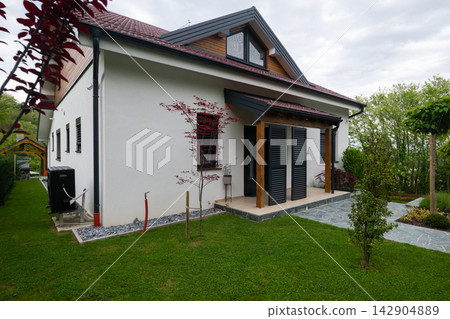 Modern suburban house exterior with covered porch and landscaped garden in spring Modern suburban house exterior with covered porch and landscaped garden in spring 142904889