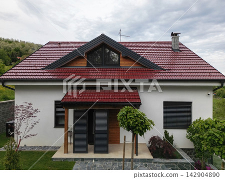 Modern countryside house with red metal roof, front porch and landscaped garden in spring daylight Modern countryside house with red metal roof, front porch and landscaped garden in spring daylight 142904890