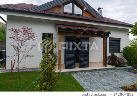 Modern suburban house entrance with covered porch, shutters and landscaped garden Modern suburban house entrance with covered porch, shutters and landscaped garden 142904891