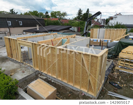 Construction of a wooden house frame with prefabricated panels on a suburban building site Construction of a wooden house frame with prefabricated panels on a suburban building site 142905017