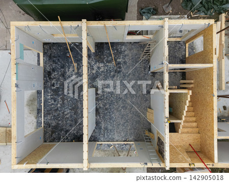 Aerial top view of wooden house construction showing interior framing, stairs and room layout on site Aerial top view of wooden house construction showing interior framing, stairs and room layout on site 142905018