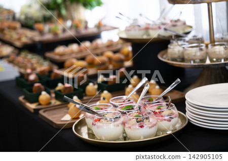 Elegant dessert buffet with individual parfaits and appetizers at a catered event or party reception Elegant dessert buffet with individual parfaits and appetizers at a catered event or party reception 142905105