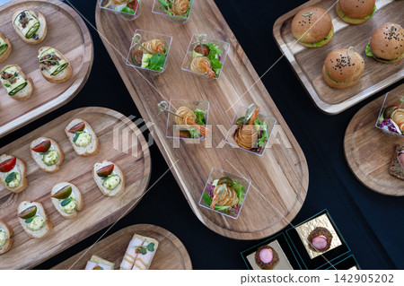 Overhead view of assorted bite-size desserts and berry parfaits on a catering buffet tray Overhead view of assorted bite-size desserts and berry parfaits on a catering buffet tray 142905202