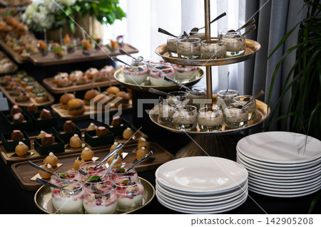 Catering buffet table with plated desserts, appetizers and stacked plates for a catered event Catering buffet table with plated desserts, appetizers and stacked plates for a catered event 142905208