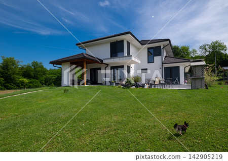 Modern modular minimalist house with solar panels, energy-efficient design and large lawn patio in a green countryside Modern modular minimalist house with solar panels, energy-efficient design and large lawn patio in a green countryside 142905219