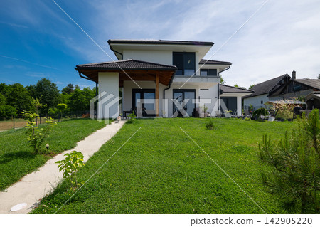 Modern modular minimalist house with solar panels and energy-efficient heating and cooling in green backyard Modern modular minimalist house with solar panels and energy-efficient heating and cooling in green backyard 142905220
