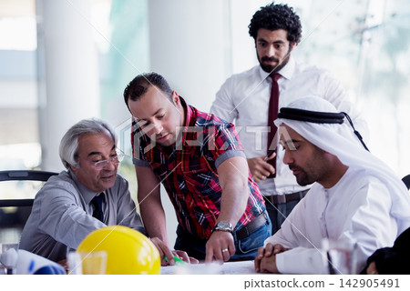 Multicultural business team collaborating on a construction project plan in a modern office meeting 142905491