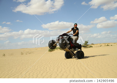 Young quad bike rider doing wheelie in desert Young quad bike rider doing wheelie in desert 142905496